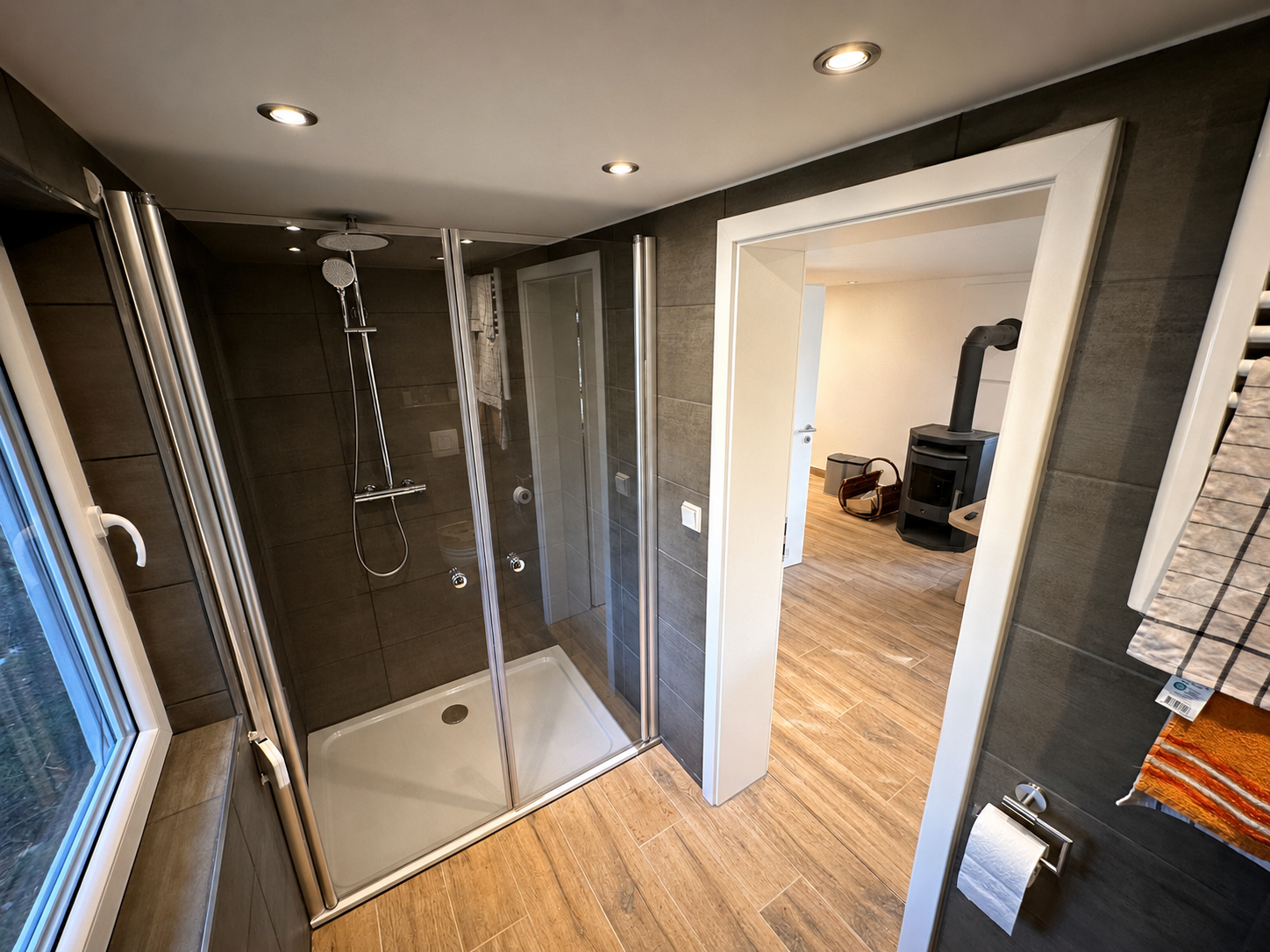 Bungalowbad mit verglaster Dusche und Blick zum Kaminofen